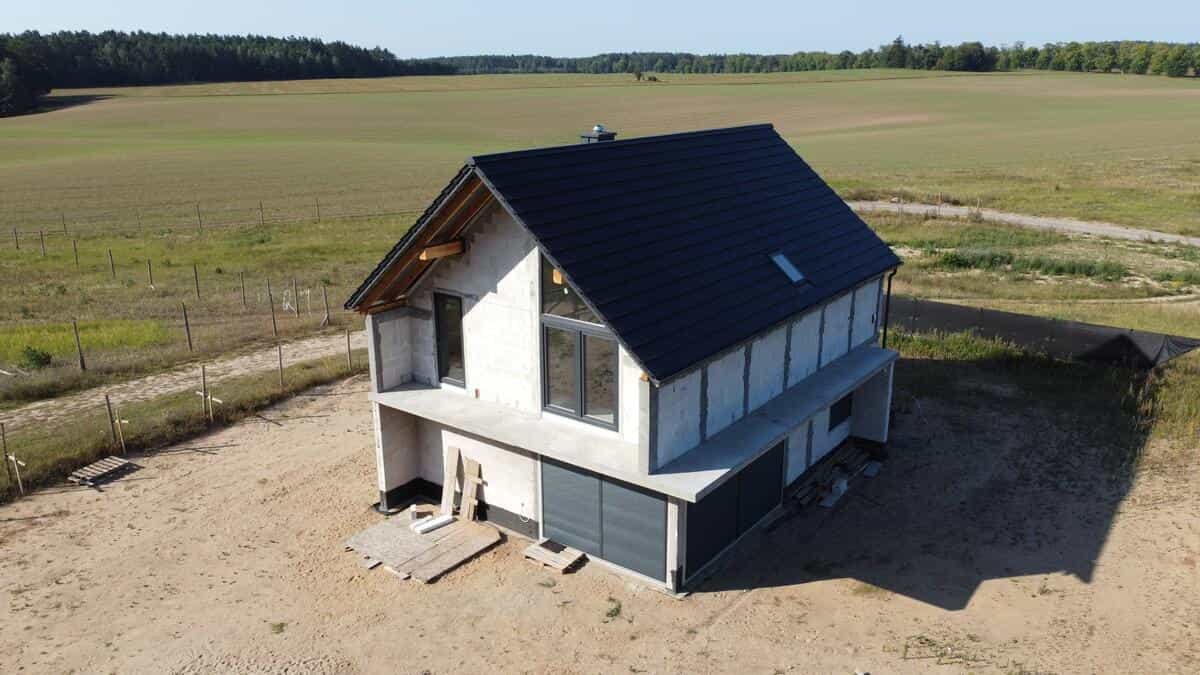 Widok frontowy domu w stanie surowym z widocznym szczytem