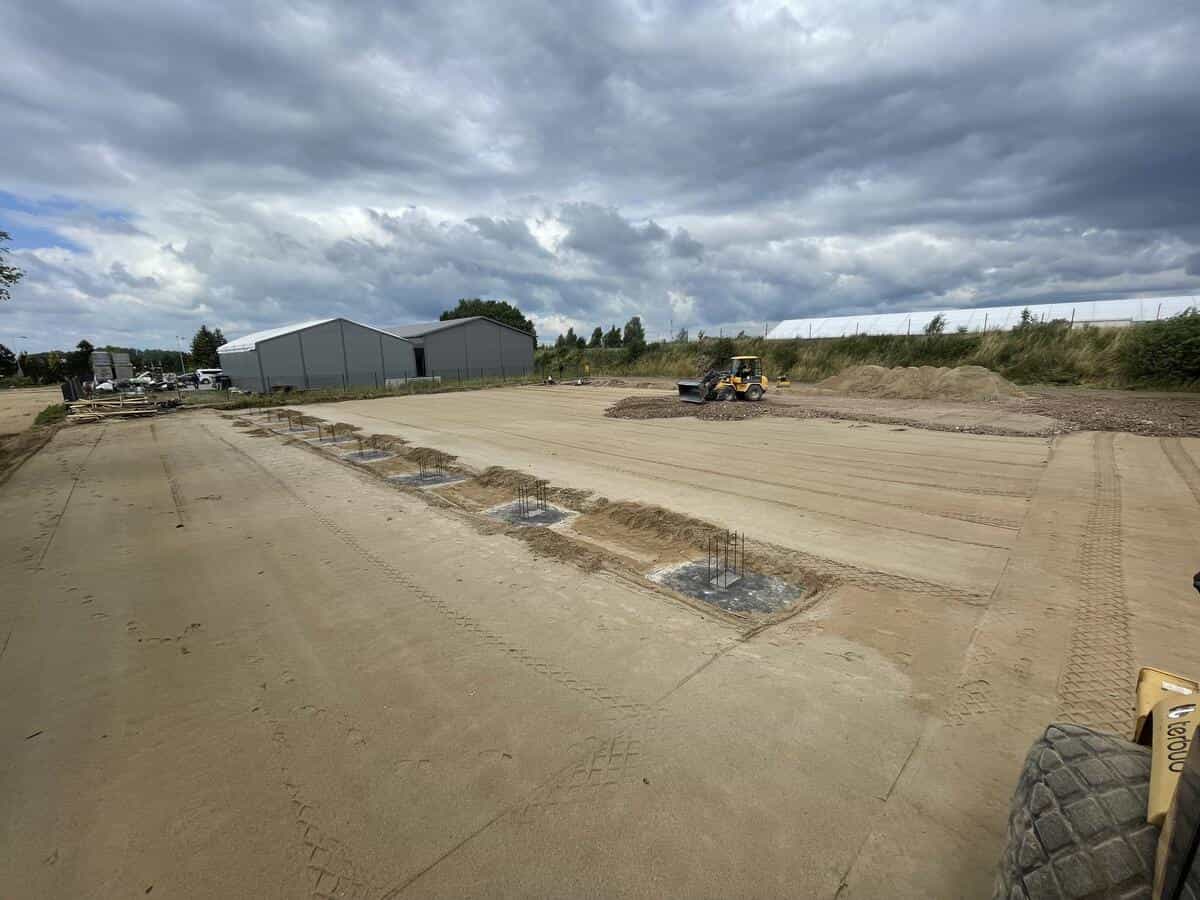 Plac budowy hali stalowej z kotwami i ciężkim sprzętem budowlanym