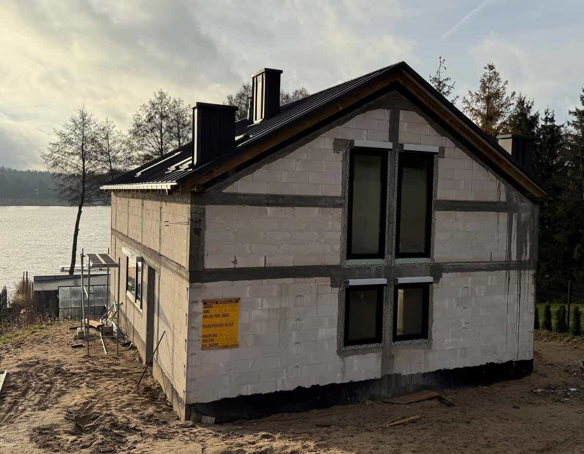 Elewacja frontowa budynku z widocznymi konstrukcjami żelbetowymi i oknami