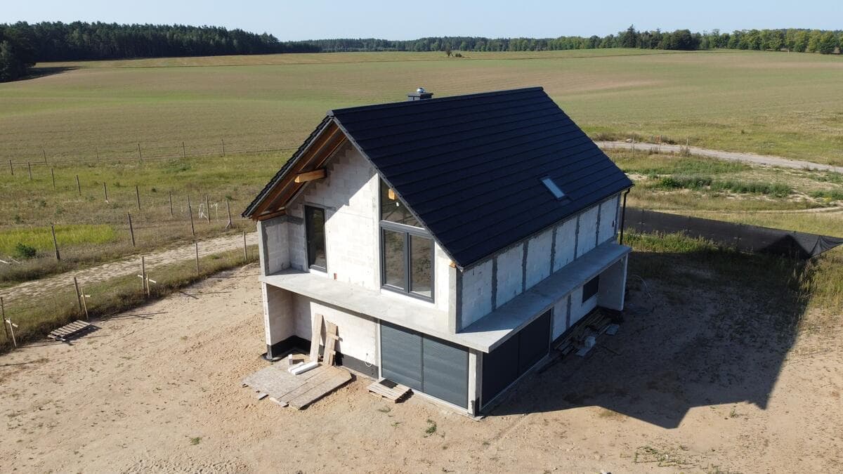 Widok frontowy domu w stanie surowym z widocznym szczytem